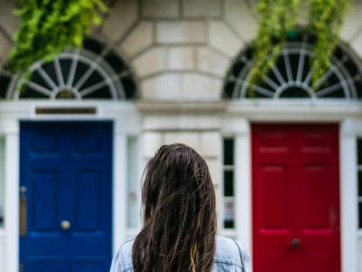 A lady staring at a blue door and a red door