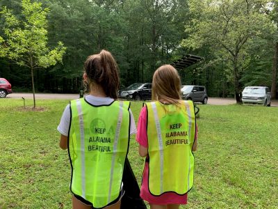 Youth picking up litter with Keep America Beautiful safety vests on.