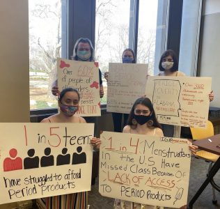 Period. Auburn volunteers gathered with informative signs about menstrual inequity