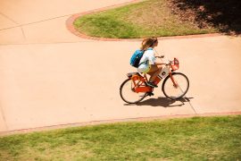 Student riding a bike share bike on campus