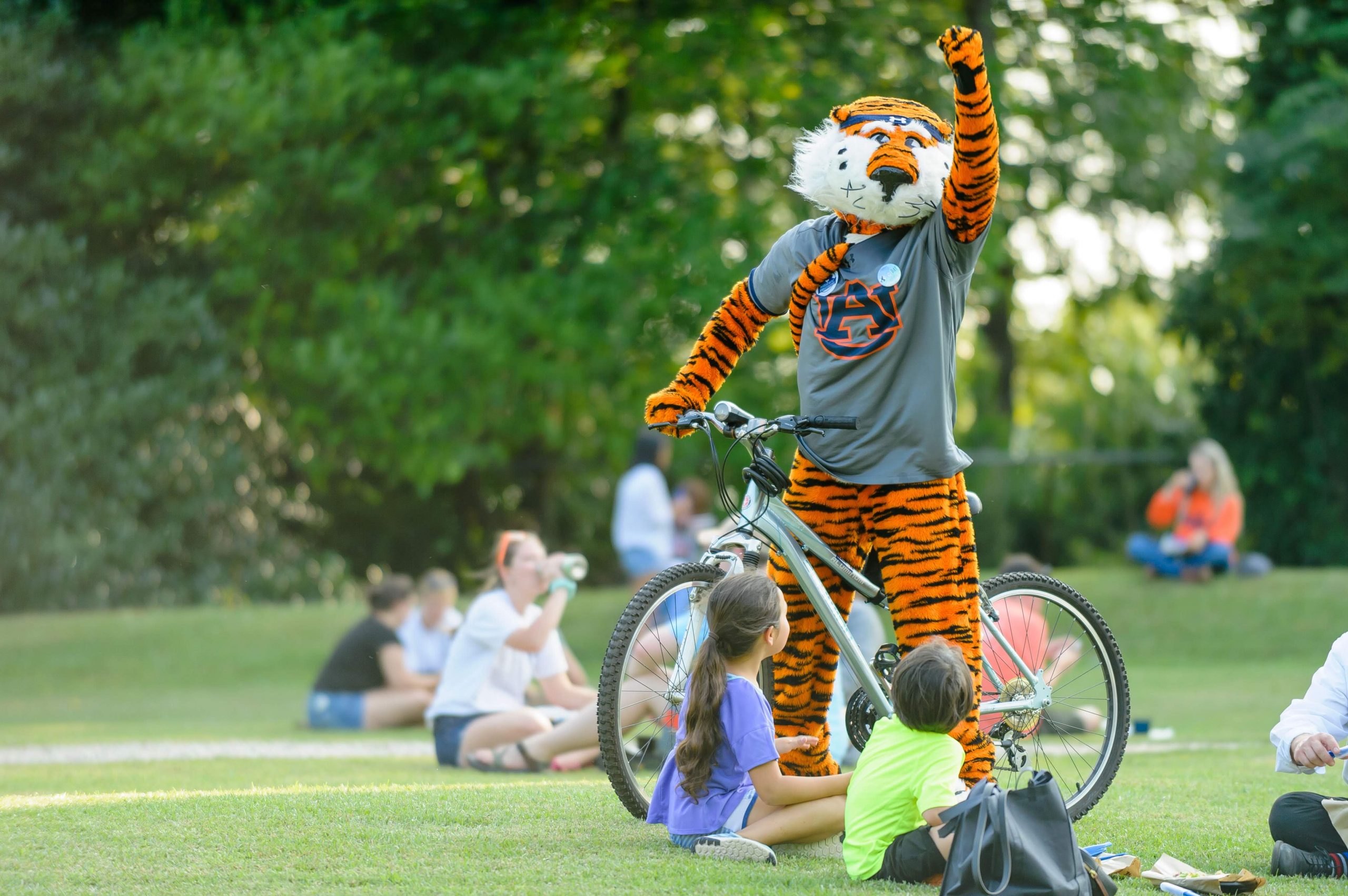 Photo of Aubie on a bicycle with his fist raised.