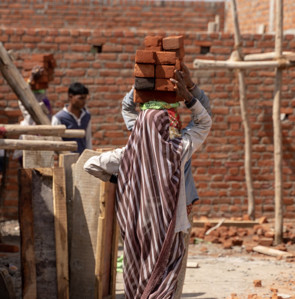 Woman carrying bricks on head SDG 8: Photo courtesy of Tim Umphreys