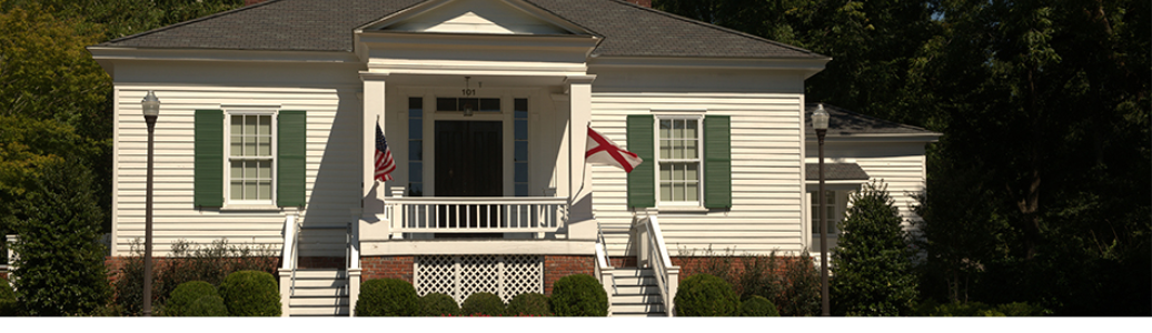 Image of pebble hill, a small white house with a green lawn in front