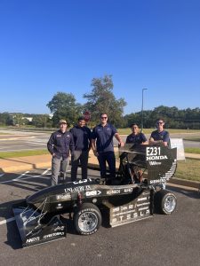 Photo of students standing with an electric racing car
