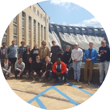 Students standing in front of a dam