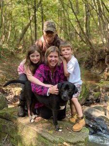 Karen, her husband, son, daughter, and dog posing in the woods