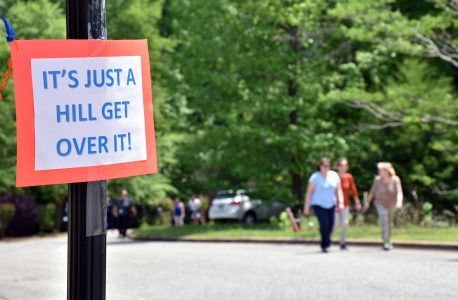 Image of a sign that reads "It's just a hill get over it!" with a group walking in the background