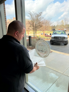 Facilities management employee decaling a window with a LEED distinction