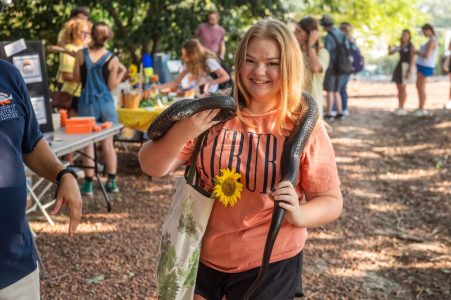 A student holds a snake after grabbing some fresh flowers. 