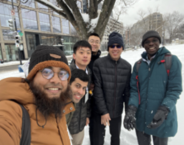 Six people standing and smiling for a selfie with snow at the background