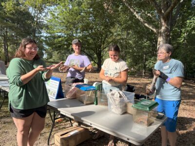Photo of a student and representatives of the Kreher Preserve & Nature Center holding snakes.