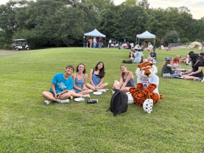 Photo students sitting with Aubie on the grass.