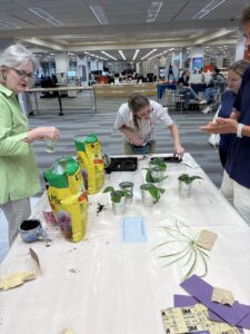 four people gathered around a table potting plants into mugs