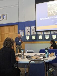A man presenting a presentation on sustainable gameday recycling