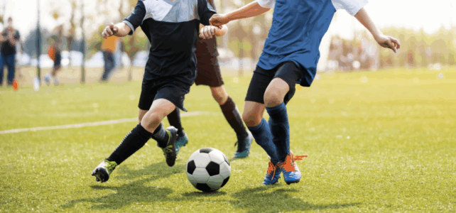 the bodies of two boys going after the ball in a soccer game