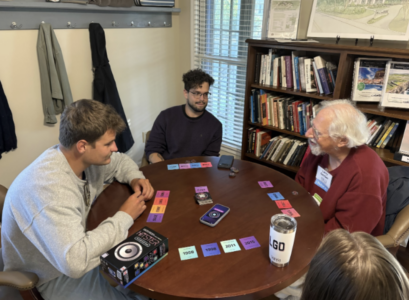 a group of mixed aged people sitting around a table playing hitster