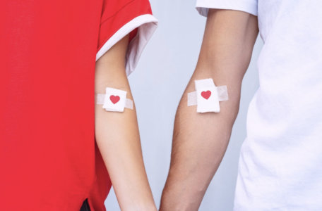 two arms beside each other with bandages that have a red heart on them