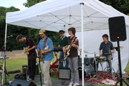 a band of five male students playing at the sustainability picnic