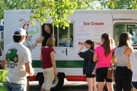 a woman handing a man an ice cream cone from the otown ice cream truck