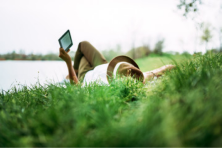 woman reading in grass on a kindle